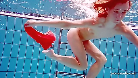 Russian redhead in dress goes swimming in the pool